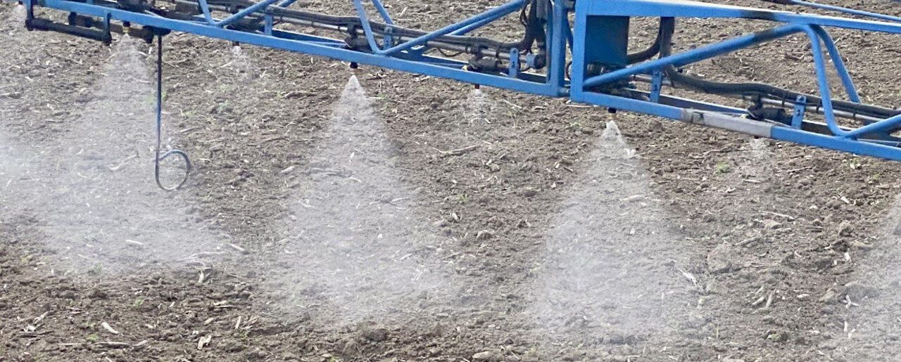 Spritzbalken im Einsatz, mehrere Düsen sprühen über den Boden